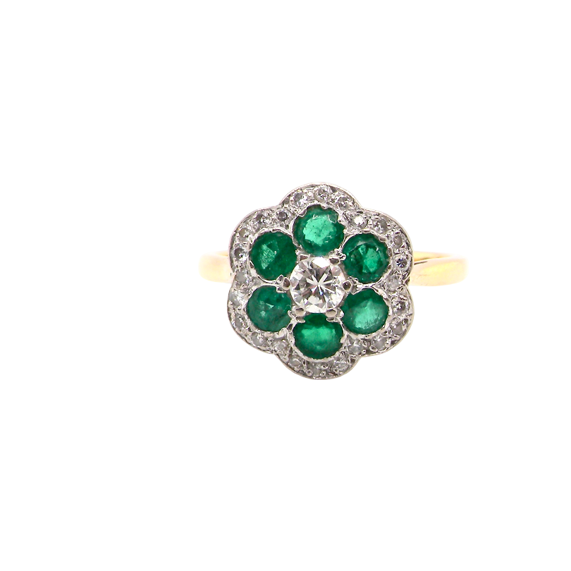 A pretty cluster ring. Features emeralds and diamonds. Centre stone a brilliant cut white diamond, measures 4mm (0.25 carats). 