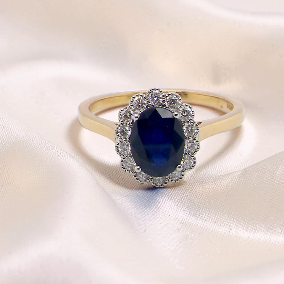 A pretty cluster ring that features an inky black blue sapphire that measures 8x6mm. Complimented by an outer border of diamonds