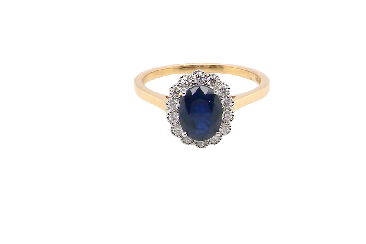 A pretty cluster ring that features an inky black blue sapphire that measures 8x6mm. Complimented by an outer border of 2mm diamonds