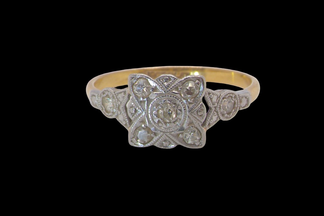 A pretty diamond cluster ring from the early part of the 20th century. A square head that has within it small white diamonds, measures 8x8mm, fancy shoulders