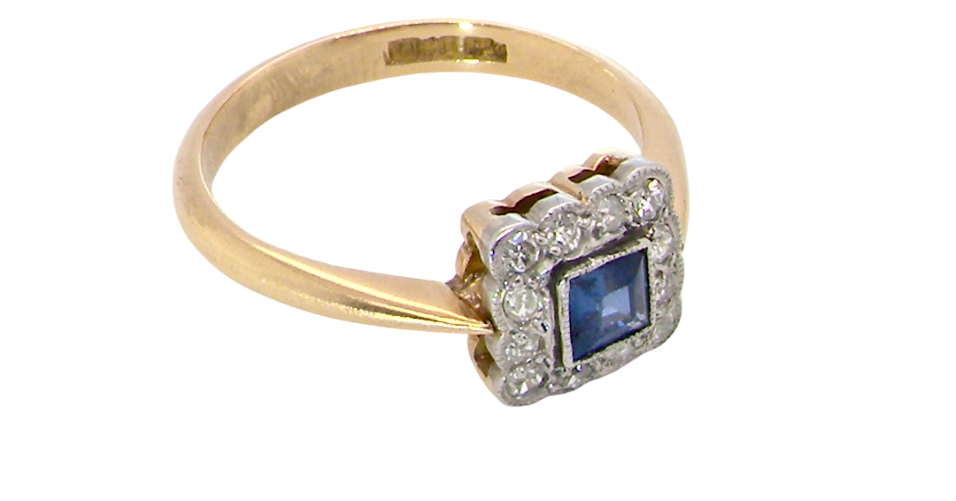 A pretty square cluster ring. Features to the centre a cornflower blue square sapphire, 4x4mm (est 0.30 carats) mille grain set.
Complimented by a halo of 1.5 mm single cut white diamonds