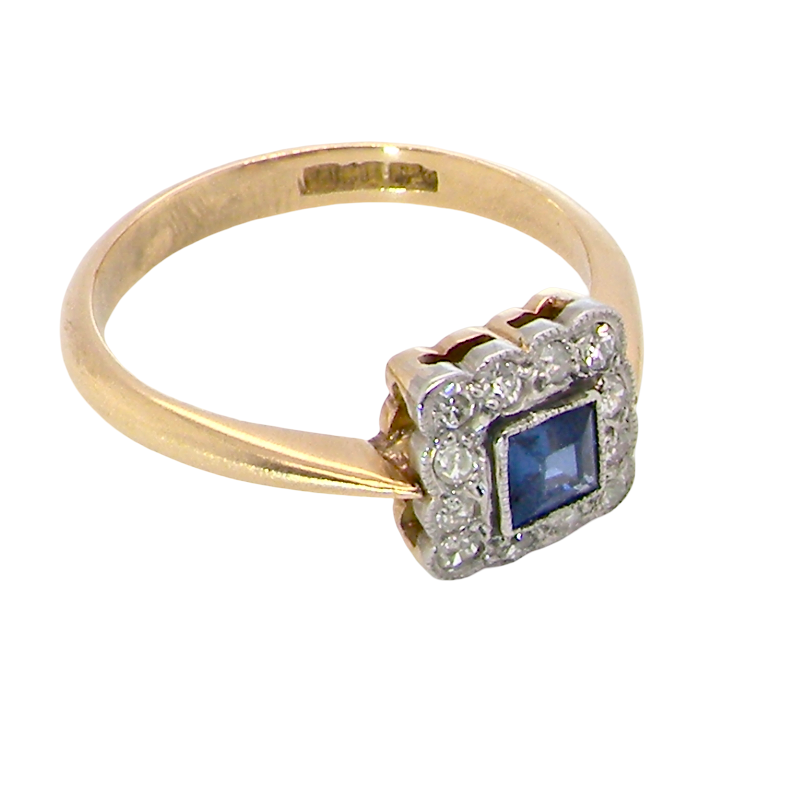 A pretty square cluster ring. Features to the centre a cornflower blue square sapphire, 4x4mm (est 0.30 carats) mille grain set.
Complimented by a halo of 1.5 mm single cut white diamonds