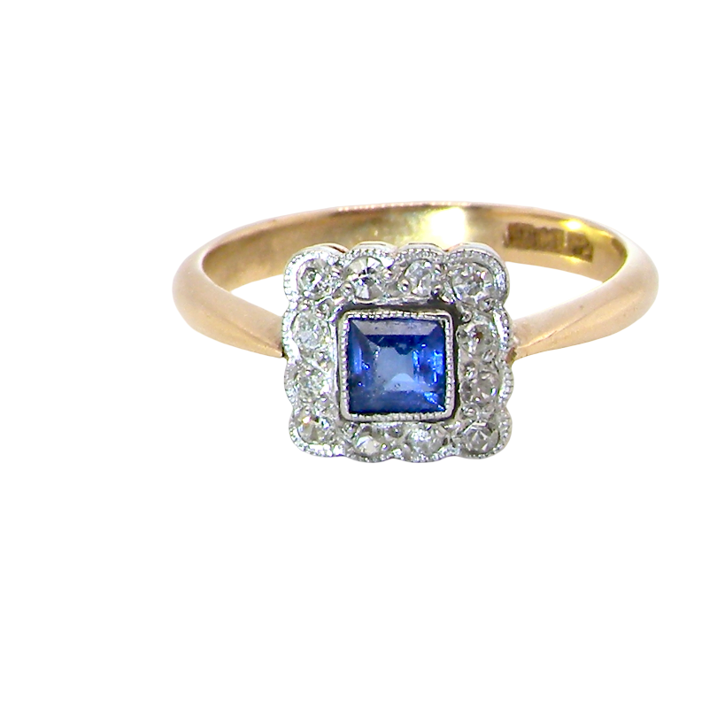 A pretty square cluster ring. Features to the centre a cornflower blue square sapphire, 4x4mm (est 0.30 carats) mille grain set.
Complimented by a halo of twelve x 1.5 mm single cut white diamonds