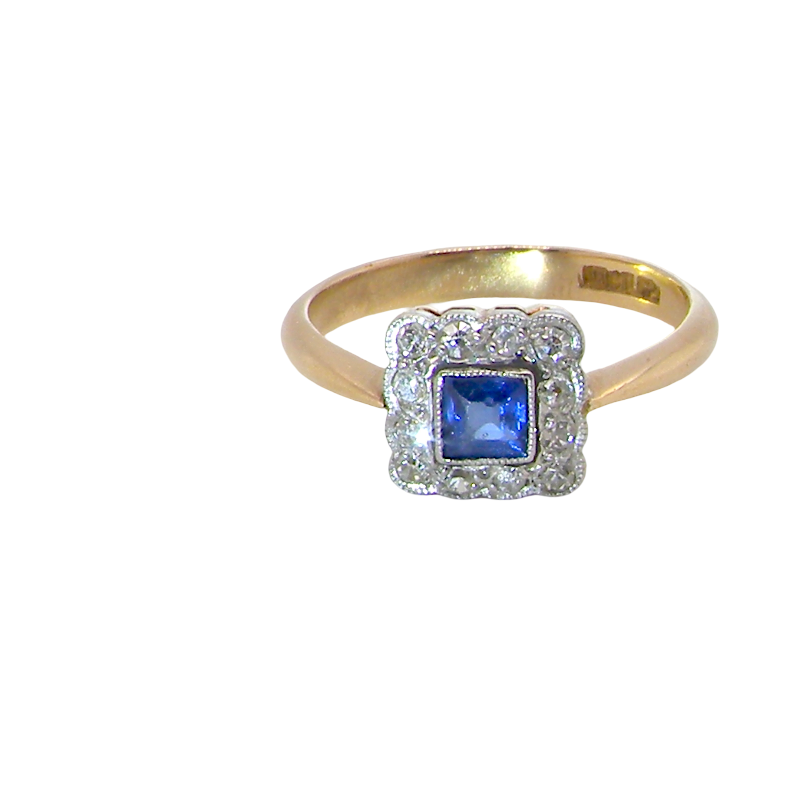 A pretty square cluster ring. Features to the centre a cornflower blue square sapphire, 4x4mm (est 0.30 carats) mille grain set.
Complimented by a halo of twelve x 1.5 mm white diamonds