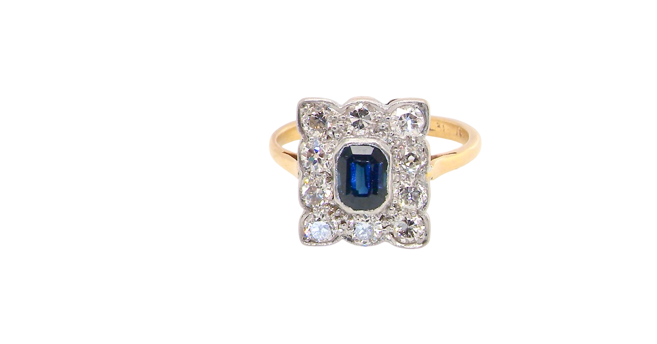 A rectangular cluster ring that features in its centre a cushion shaped dark blue sapphire, that measures 5x3.5mm (est 0.30 carats)
