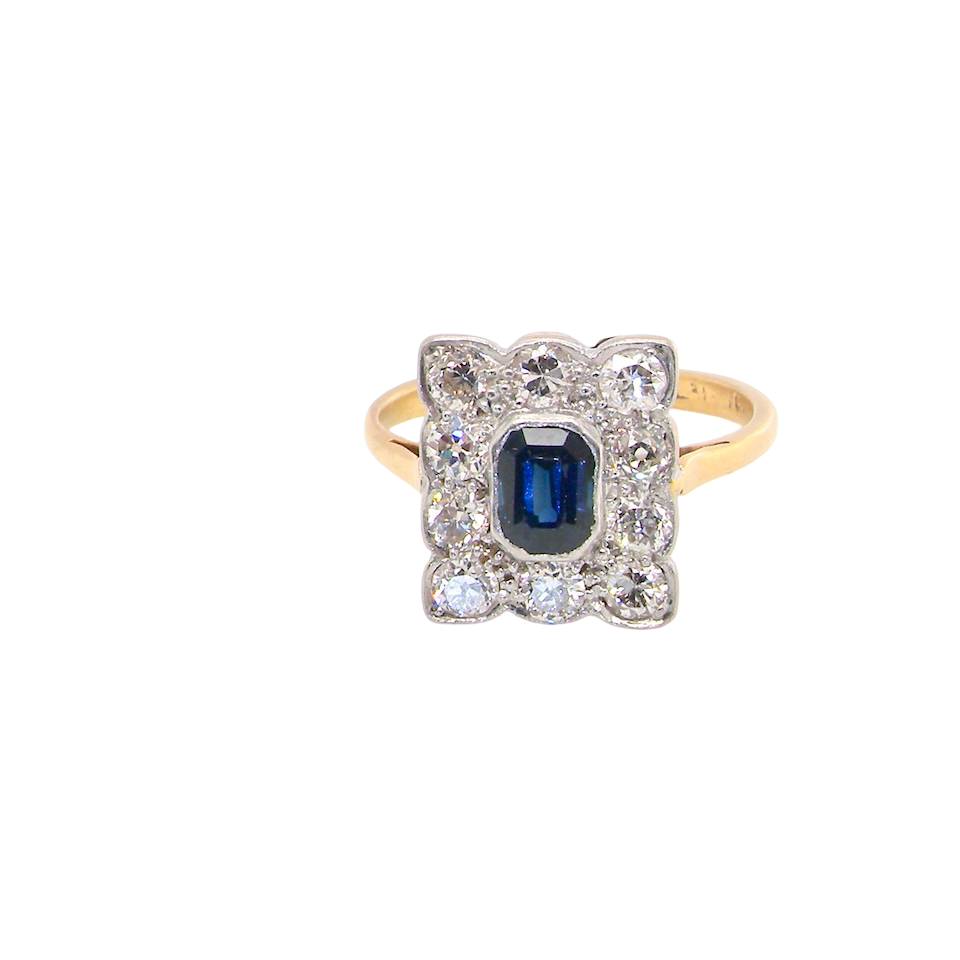 A rectangular cluster ring that features in its centre a cushion shaped dark blue sapphire, that measures 5x3.5mm (est 0.30 carats)