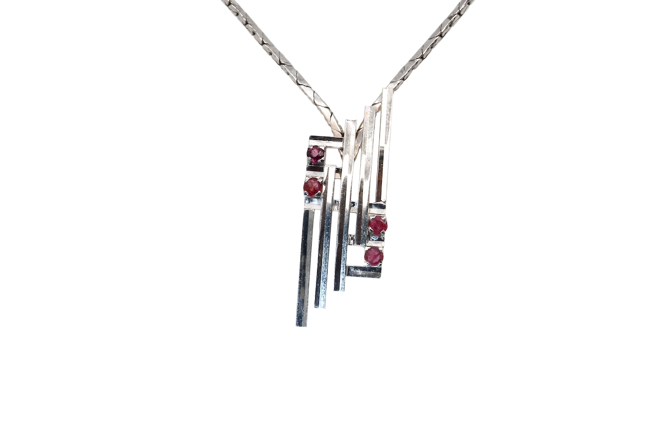 A striking modern pendant set with four 3mm rubies. The pendant measures 40mm x 14mm and features a sleek design of five horizontal bars, with the outer bars each set with vibrant round rubies.