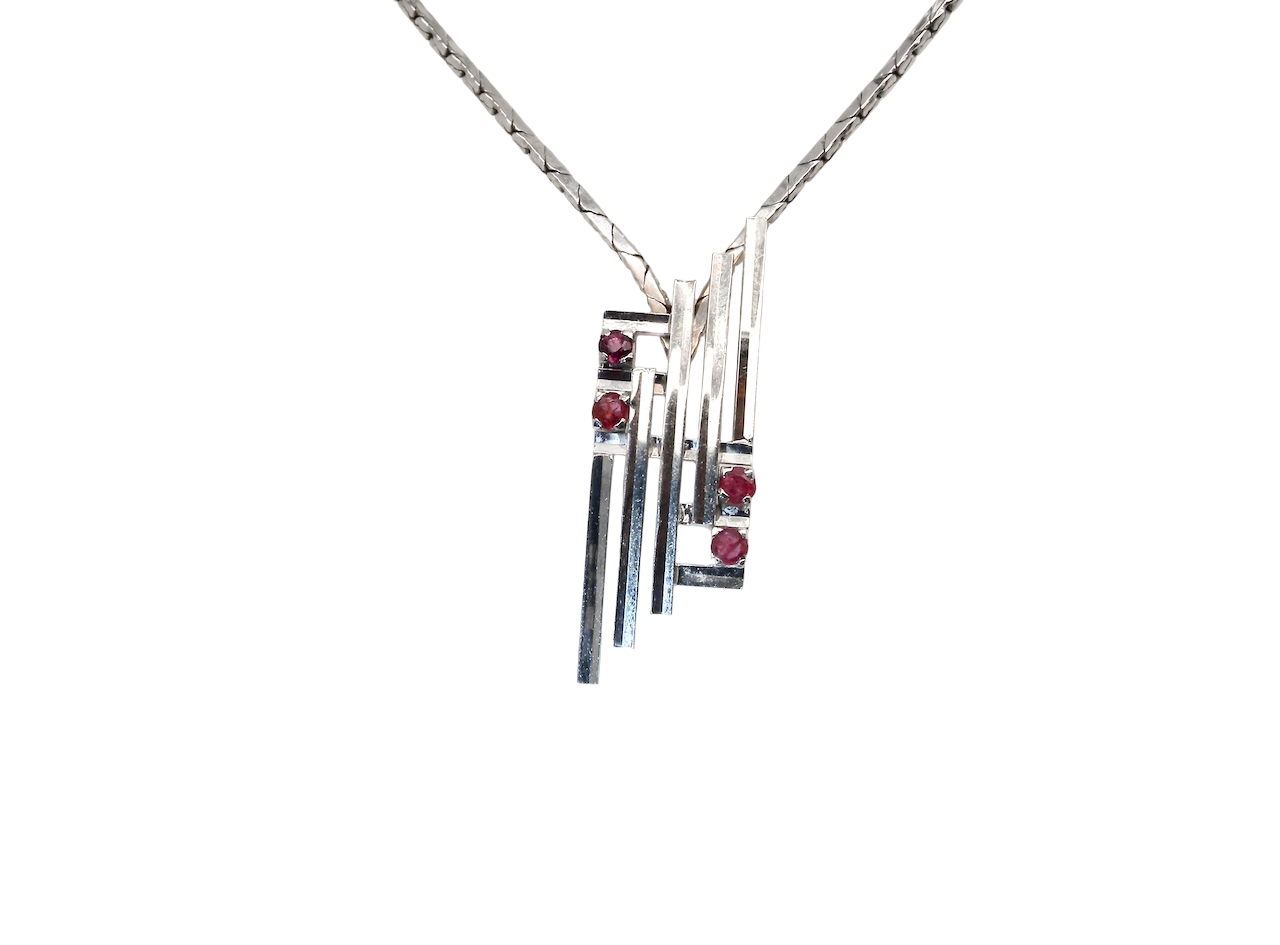 A striking modern pendant set with four 3mm rubies. The pendant measures 40mm x 14mm and features a sleek design of five horizontal bars, with the outer bars each set with vibrant round rubies.