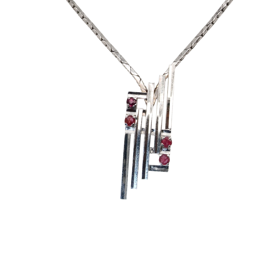 A striking modern pendant set with four 3mm rubies. The pendant measures 40mm x 14mm and features a sleek design of five horizontal bars, with the outer bars each set with vibrant round rubies.