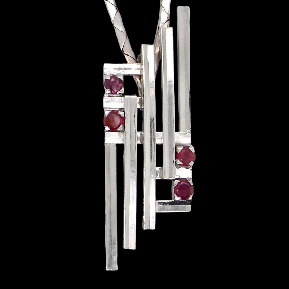 A striking modern pendant set with four 3mm rubies. The pendant measures approximately 40mm x 14mm and features a design of five horizontal bars, with the outer bars each set with vibrant round rubies.