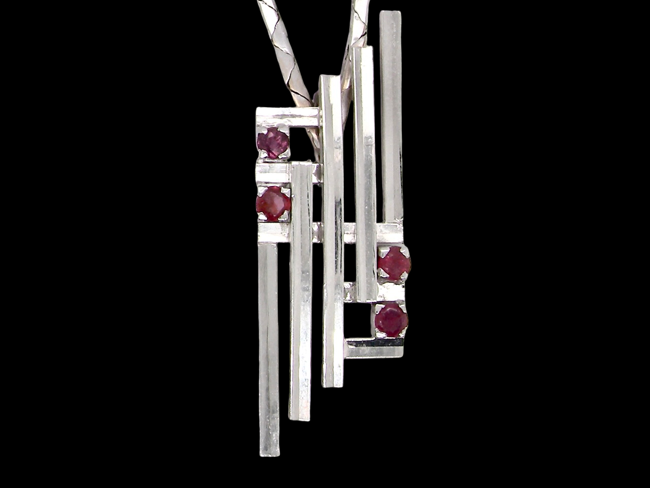 A striking modern pendant set with four 3mm rubies. The pendant measures approximately 40mm x 14mm and features a design of five horizontal bars, with the outer bars each set with vibrant round rubies.
