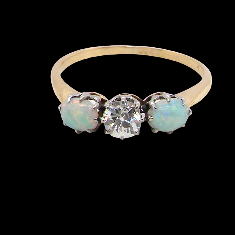 A three stone ring, the centre stone an old brilliant cut white diamond 4.6mm (est 0.38 carats) opal