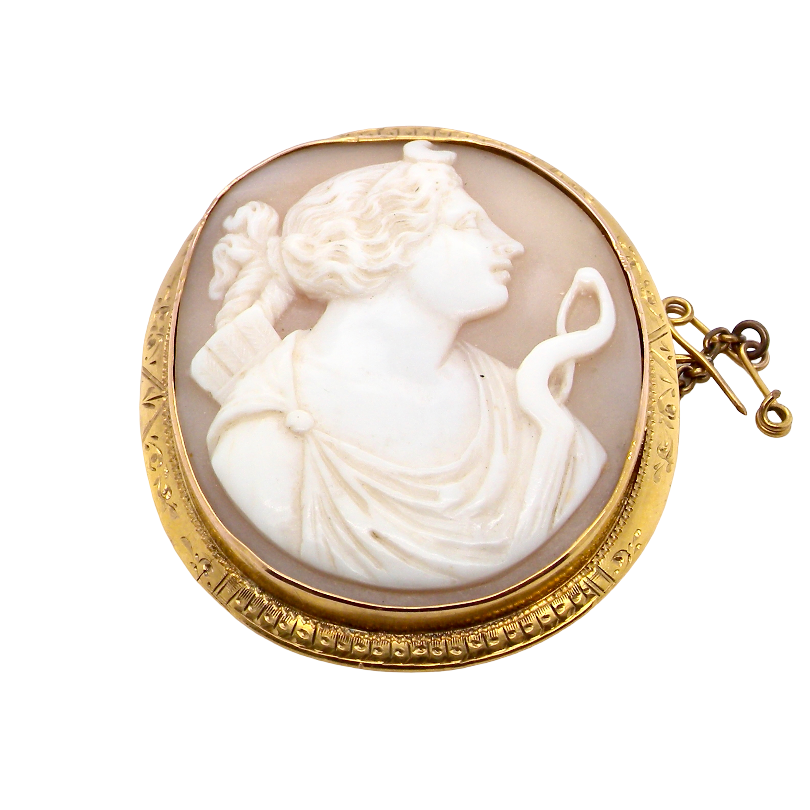 An antique-style oval cameo brooch featuring a carved white classical female profile on a warm beige background, set in a gold-toned bezel with a small gold clasp, shown on a plain white background.