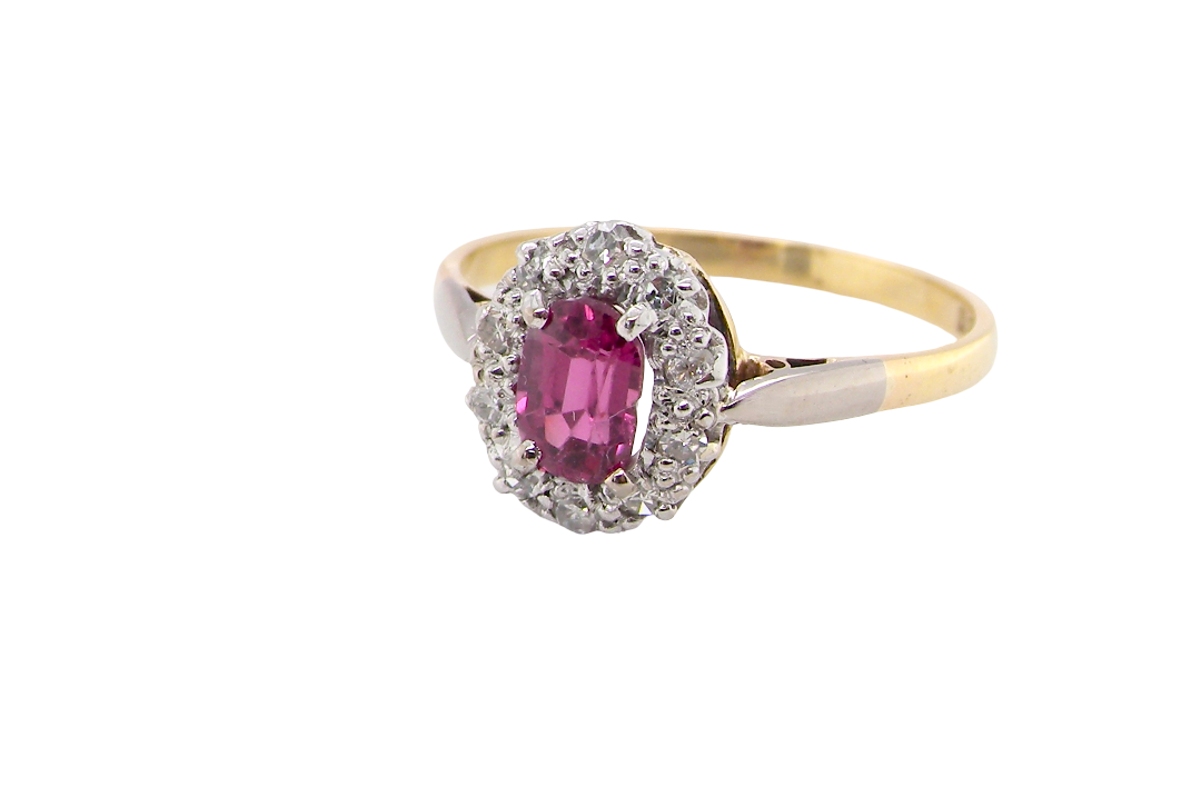 A traditional cluster ring. Features to the centre a dark pink red ruby, oval cut 6x4mm