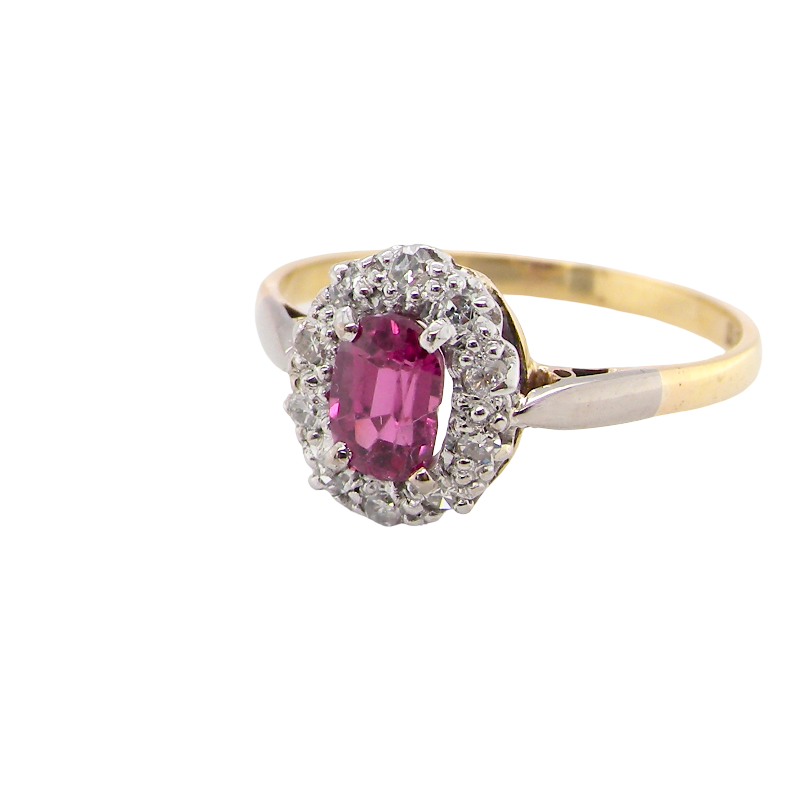A traditional cluster ring. Features to the centre a dark pink red ruby, oval cut 6x4mm