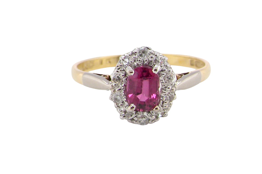 A traditional cluster ring. Features to the centre a dark pink red ruby, oval cut 6x4mm (0.50 carats)