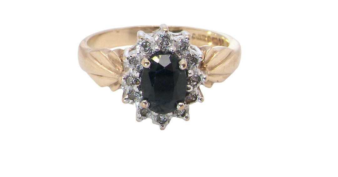 A traditional cluster ring that features to the centre a dark black blue oval cut sapphire 7x5mm claw set.