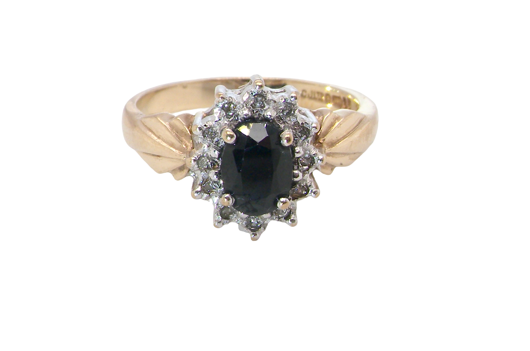 A traditional cluster ring that features to the centre a dark black blue oval cut sapphire 7x5mm claw set.