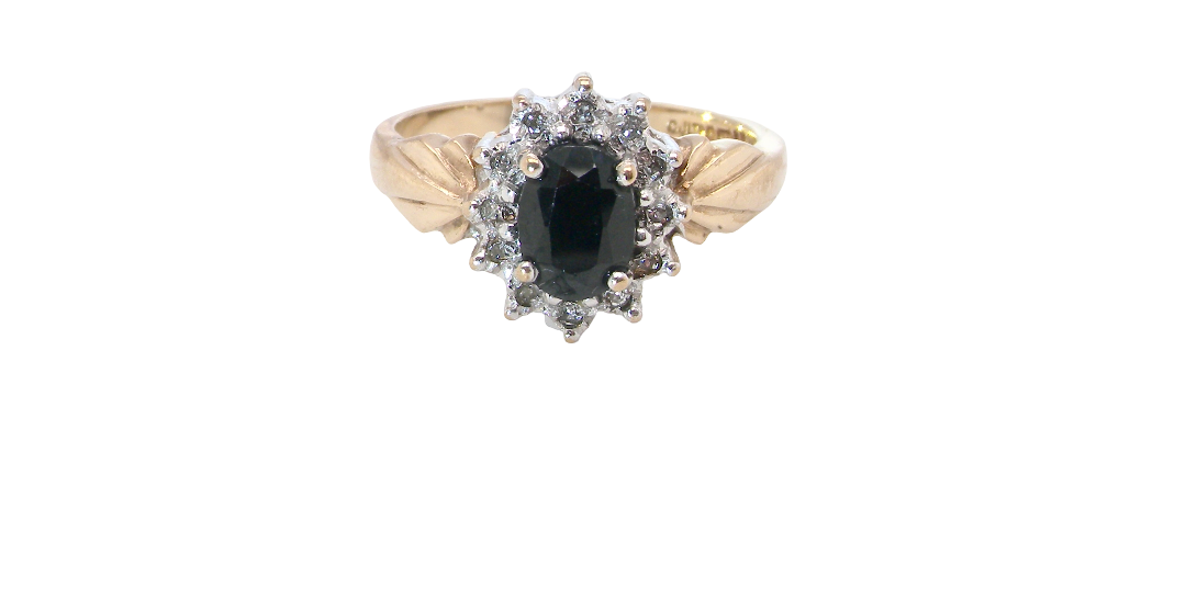 A traditional cluster ring that features to the centre a dark black blue oval cut sapphire 7x5mm (est 3/4 ct) claw set.