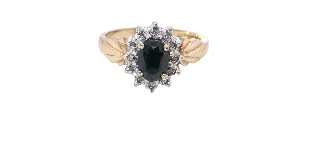 A traditional cluster ring that features to the centre a dark black blue oval cut sapphire 7x5mm (est 3/4 ct) claw set.