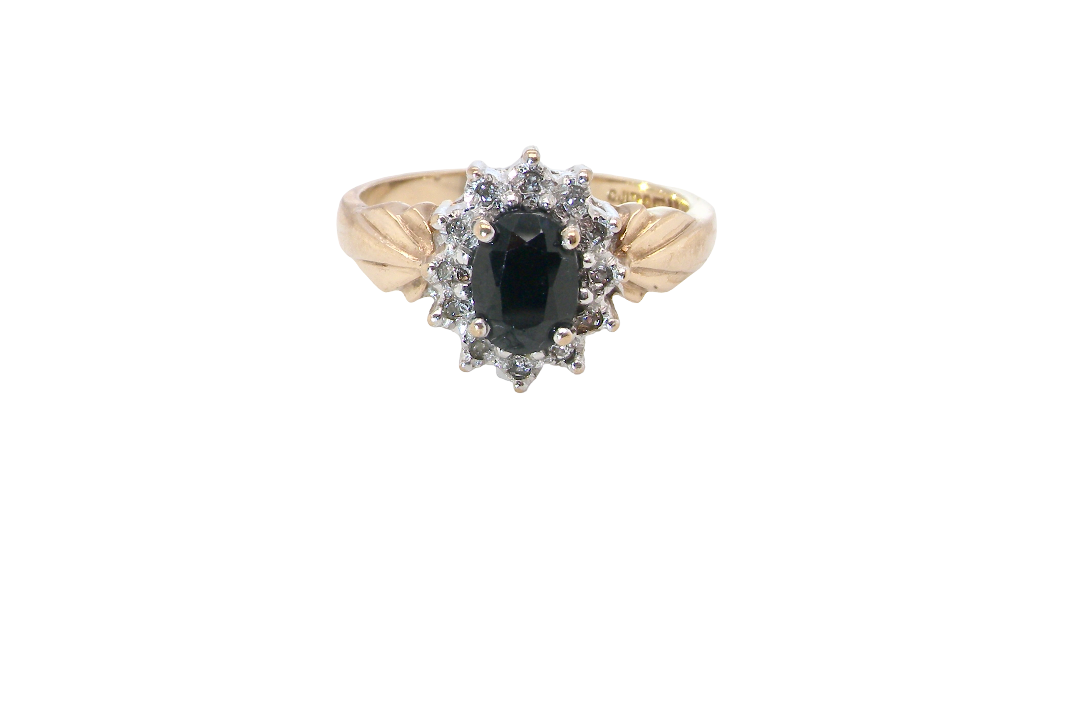 A traditional cluster ring that features to the centre a dark black blue oval cut sapphire 7x5mm (est 3/4 ct) claw set.