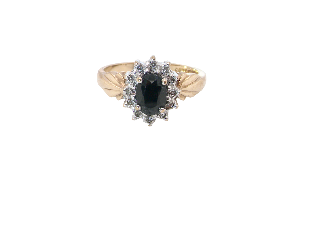 A traditional cluster ring that features to the centre a dark black blue oval cut sapphire 7x5mm (est 3/4 ct) claw set.