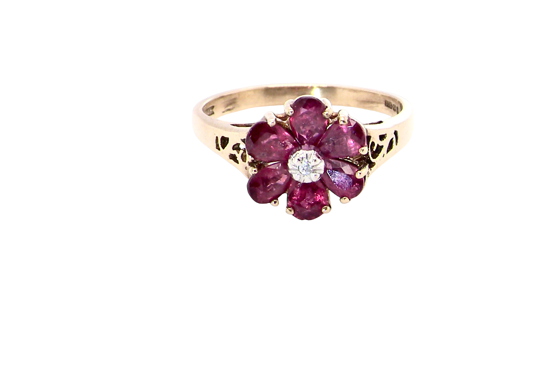 A very pretty 9 carat gold cluster ring. The centre stone a small illusion set diamond, 1.3mm
Surrounded by six pear shaped red rubies,