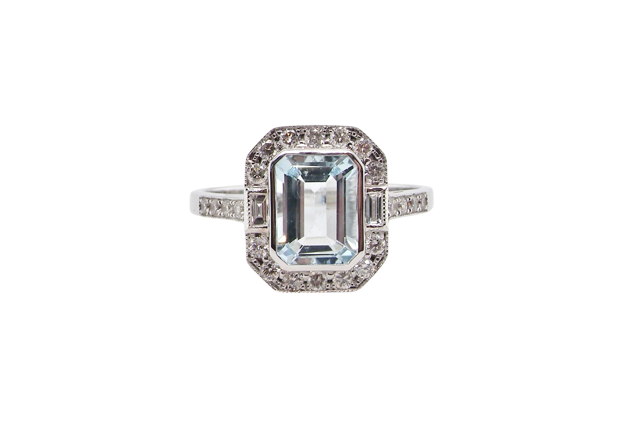A very pretty cluster ring. Features a step cut aquamarine centre stone, 8x7mm (est 1.21 carats). Plain rim setting.