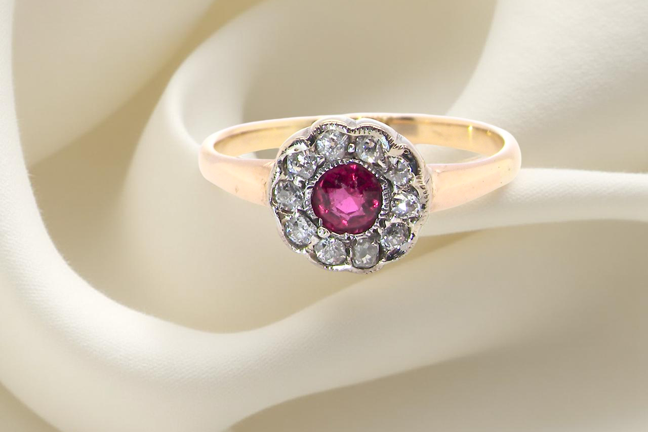 A very pretty vintage daisy cluster ring. Features to the centre a round pink red ruby that measures 4mm,