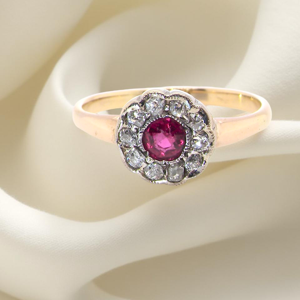 A very pretty vintage daisy cluster ring. Features to the centre a round pink red ruby that measures 4mm,