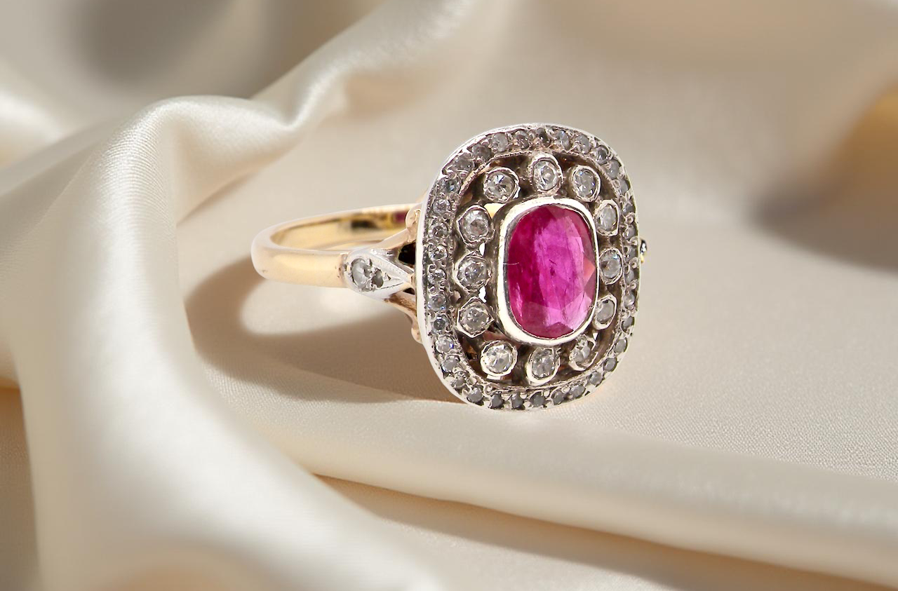 Gold ring with a pink gemstone and diamond accents on beige fabric