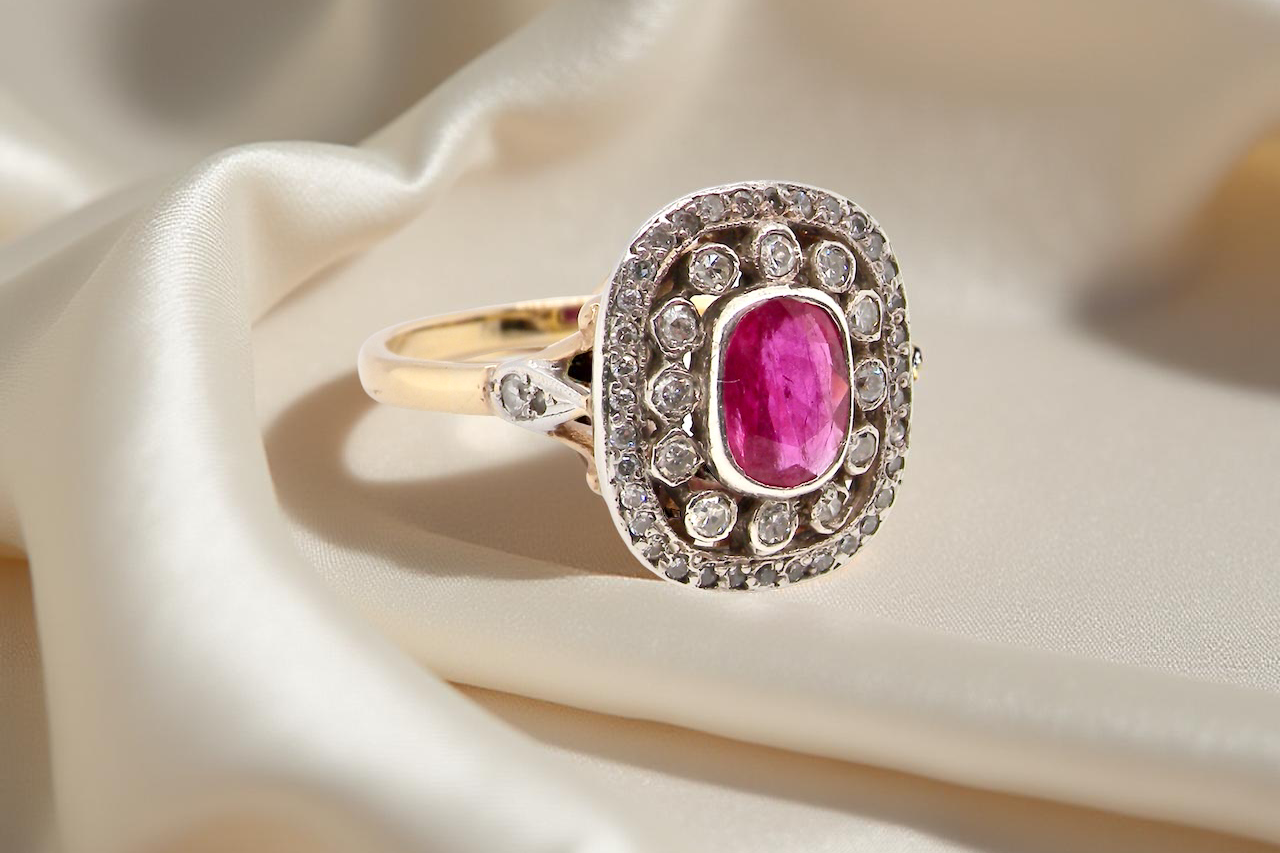 Gold ring with a pink gemstone and diamond accents on beige fabric