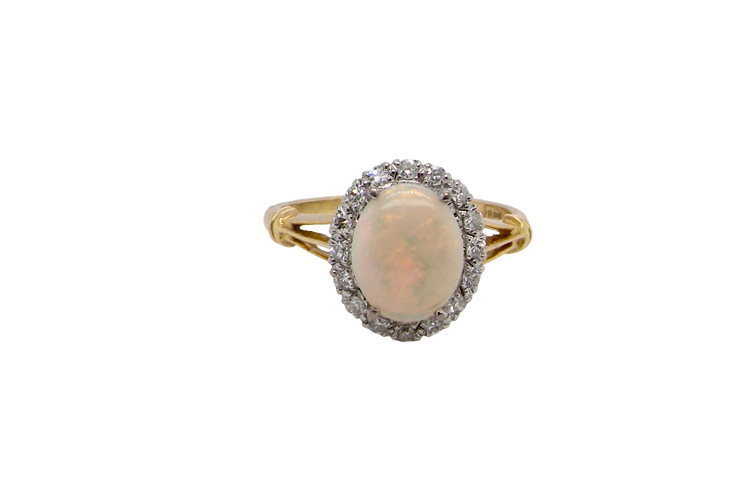 A vintage cluster ring. Features an oval white opal, measures 10x8mm, with a good play of colour.