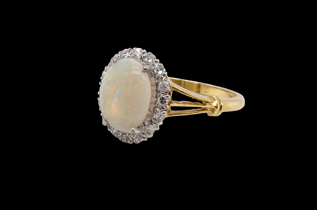 A vintage cluster ring. Features an oval white opal, measures 10x8mm, with a good play of colour. side