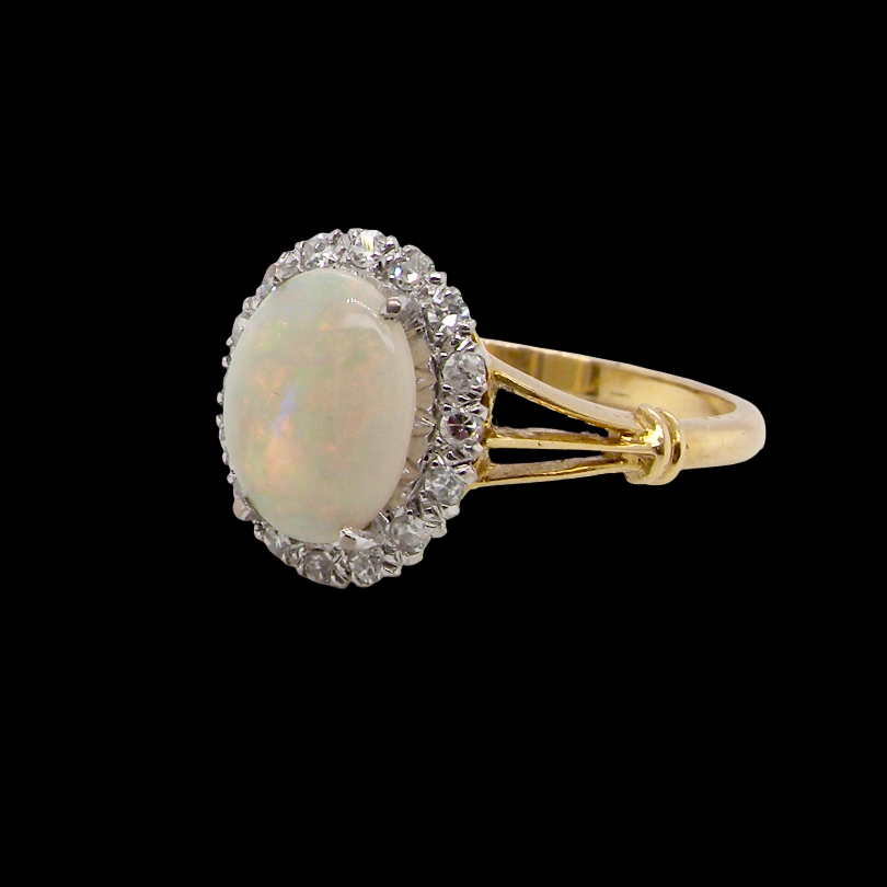 A vintage cluster ring. Features an oval white opal, measures 10x8mm, with a good play of colour. side