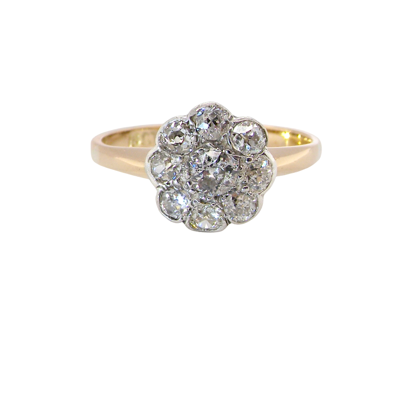 A vintage-style cluster ring featuring a central cluster of round diamonds in a silver-toned setting, mounted on a yellow gold band, shown against a plain white background.