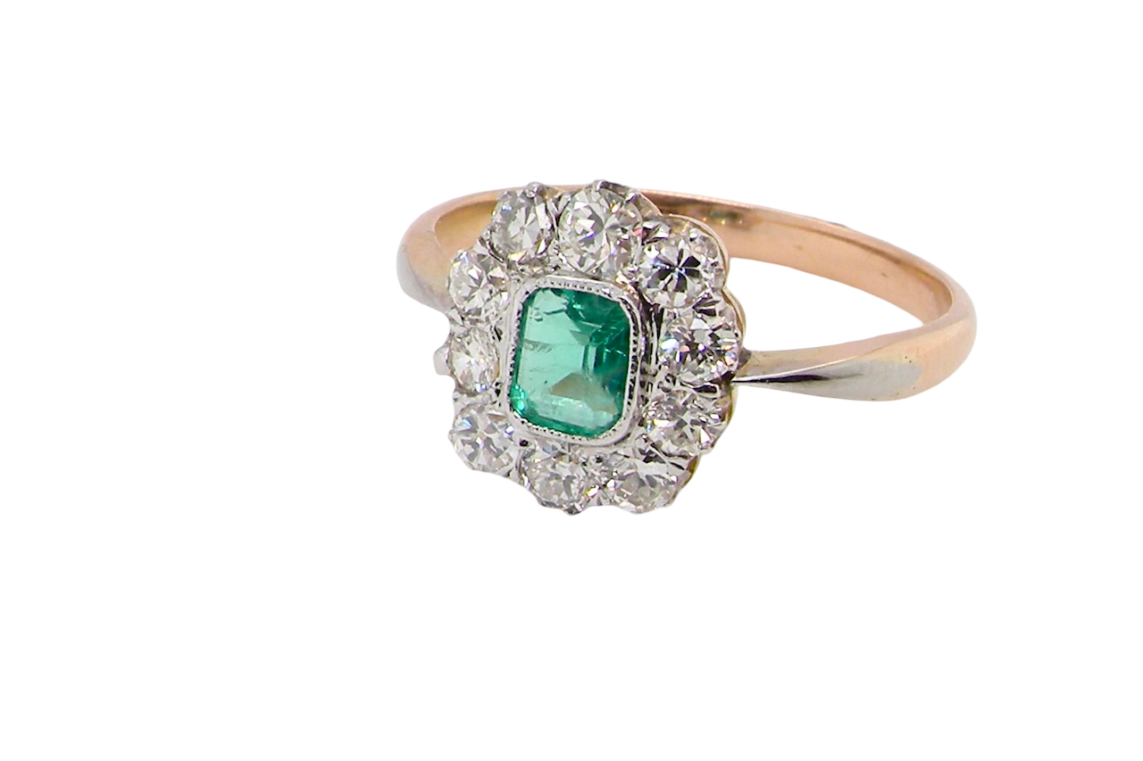 A vintage cluster ring, the centre stone a cushion shaped emerald 4x3.5mm, Mille grain setting.
