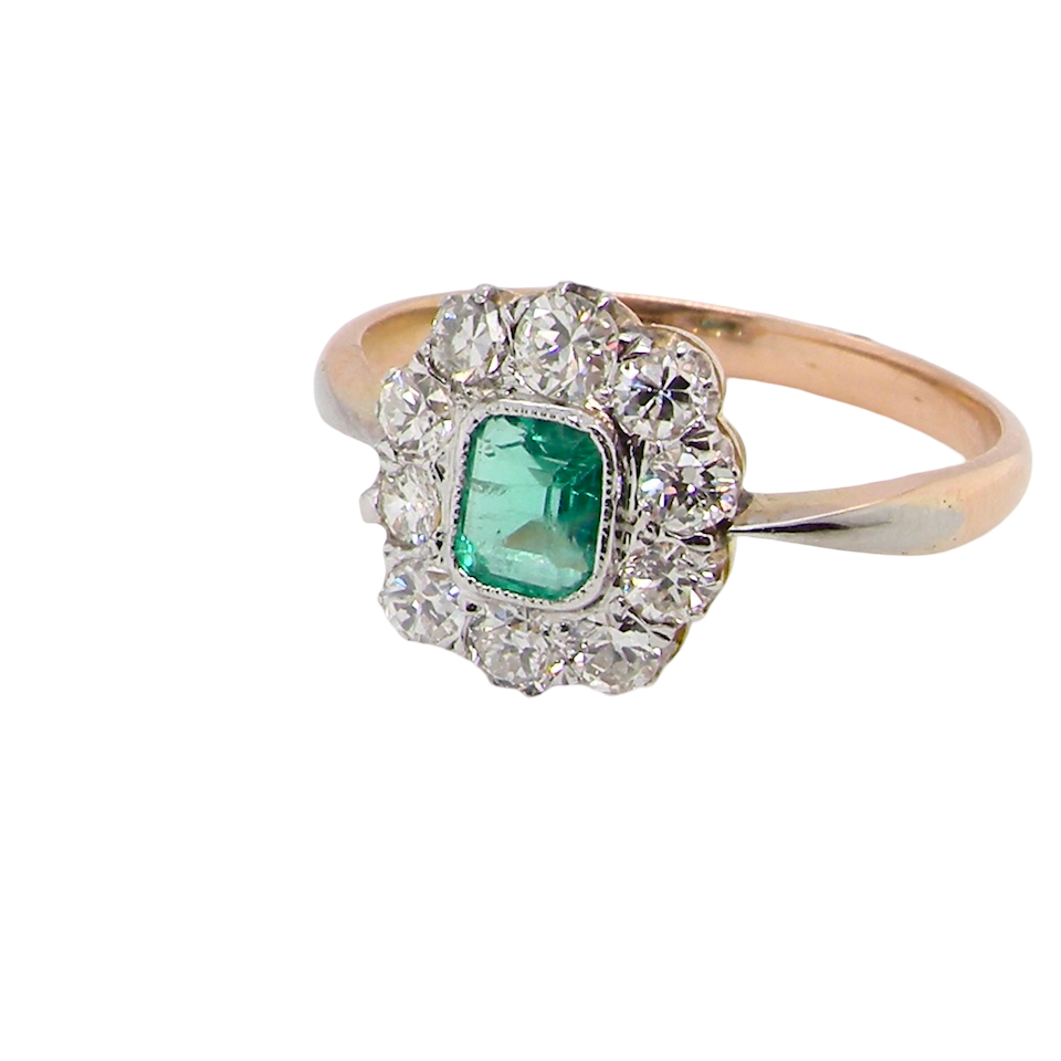 A vintage cluster ring, the centre stone a cushion shaped emerald 4x3.5mm, Mille grain setting.