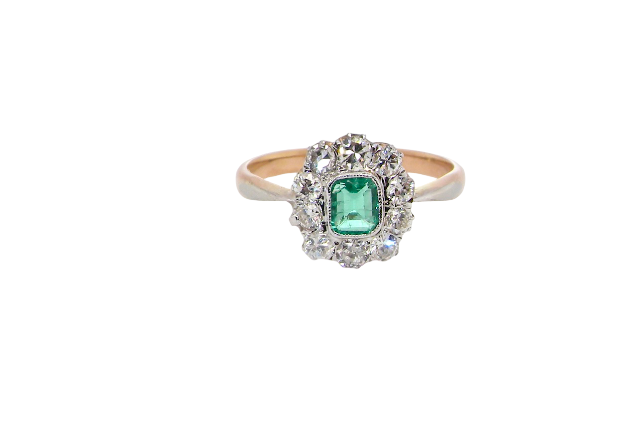 A vintage cluster ring, the centre stone a cushion shaped emerald 4x3.5mm, mid to dark green colour. Mille grain setting.