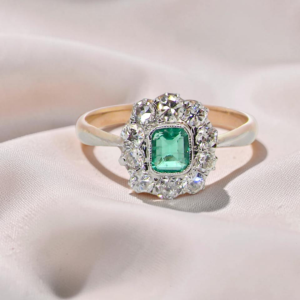cluster ring, the centre stone a cushion shaped emerald 4x3.5mm, mid to dark green colour. Mille grain setting.
