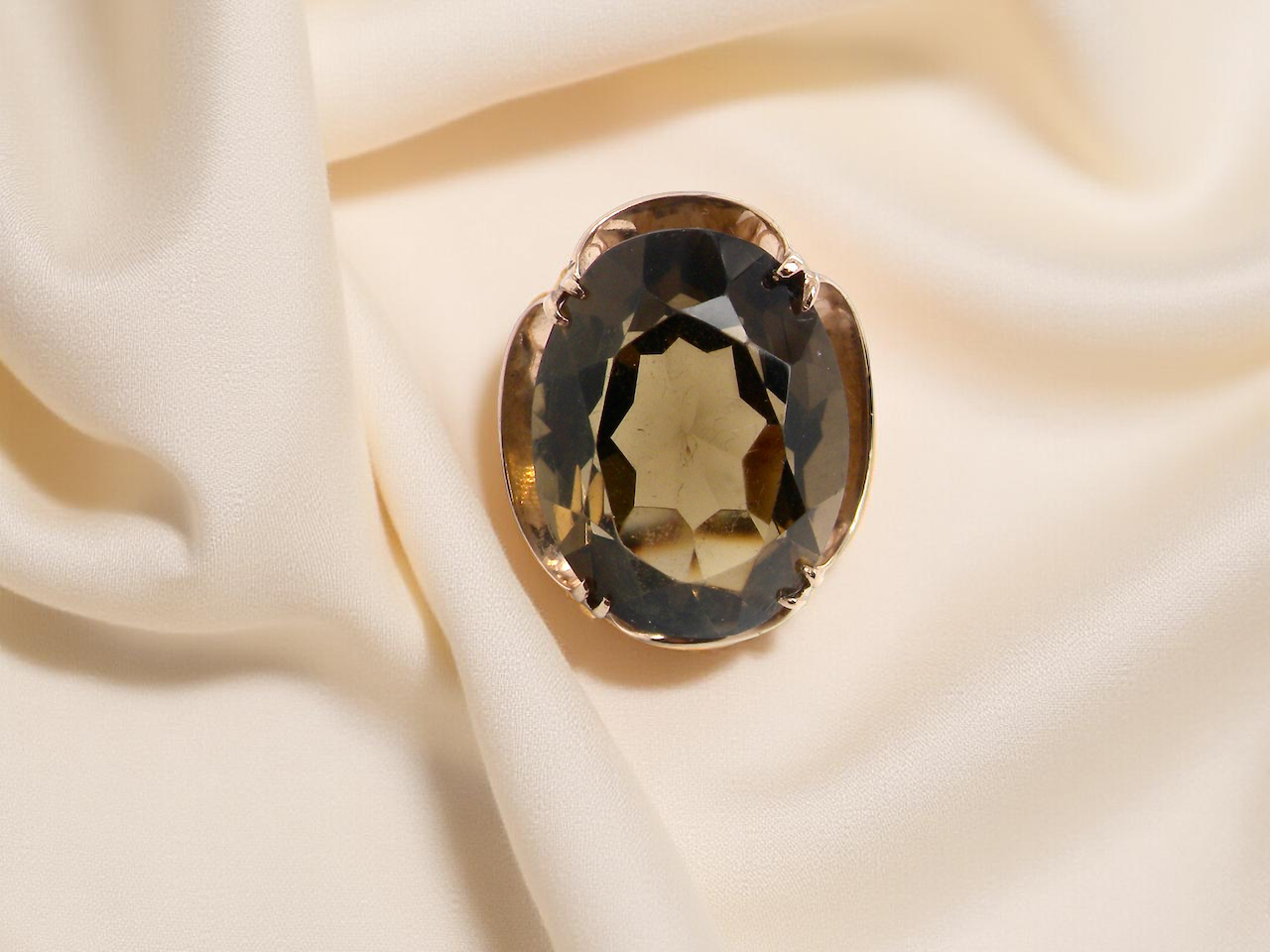 Gold ring with a smoky topaz stone on a beige fabric background