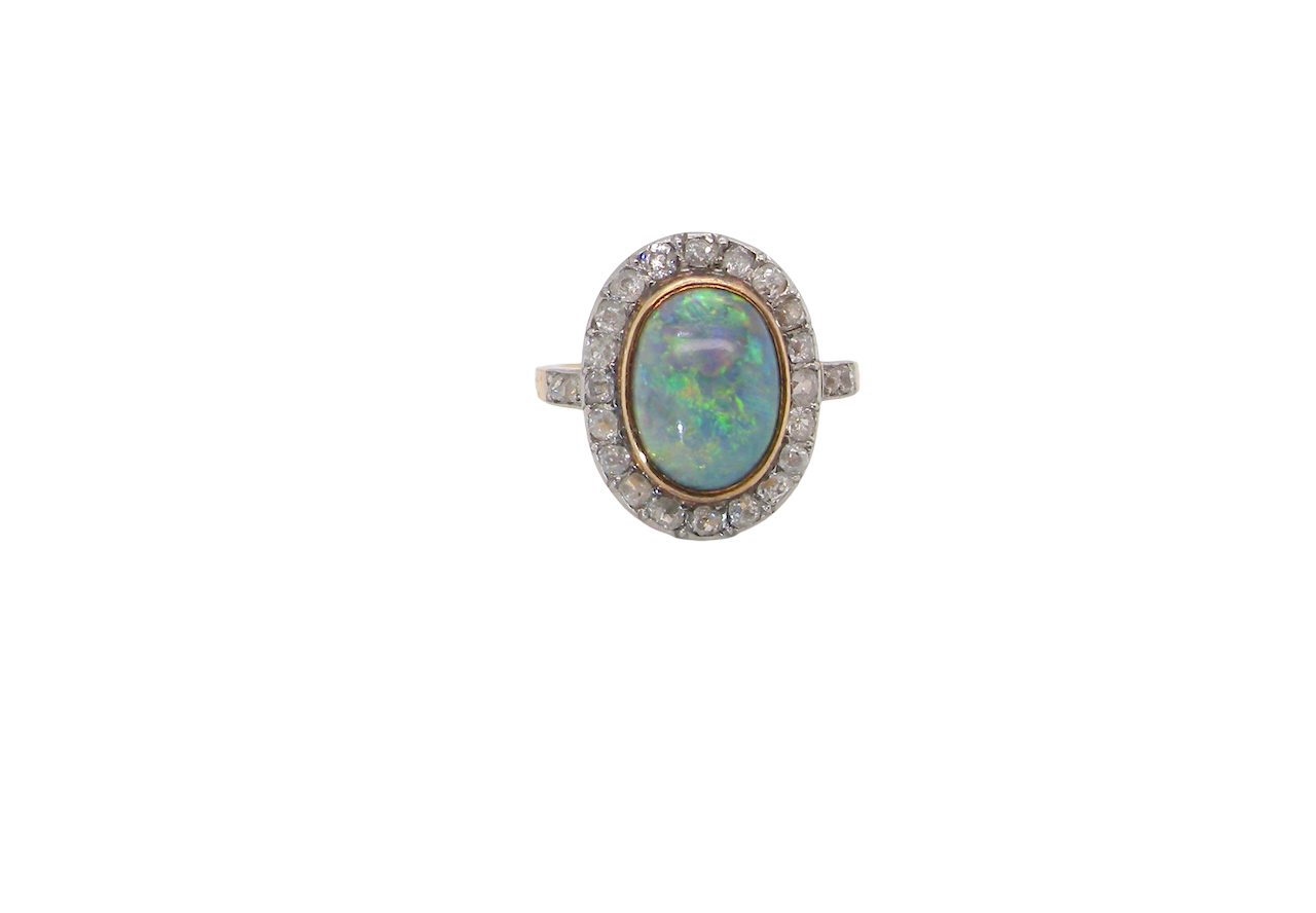 A vintage early 20th century cluster ring. Features to the centre a black opal doublet, with an excellent play of colour, measures 9.5x7.5mm, in a rim setting.