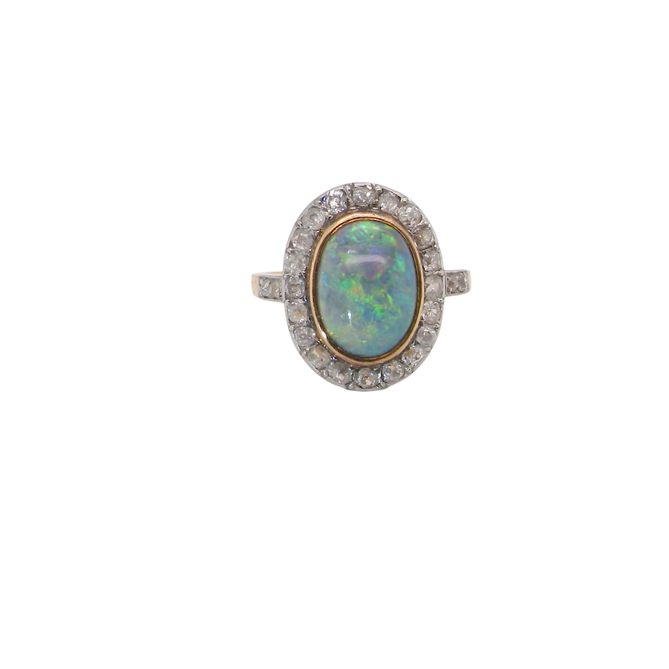 A vintage early 20th century cluster ring. Features to the centre a black opal doublet, with an excellent play of colour, measures 9.5x7.5mm, in a rim setting.