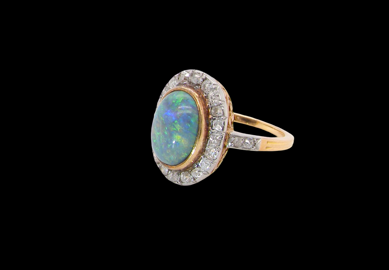 A vintage early 20th century cluster ring. Features to the centre a black opal doublet, with an excellent play of colour, measures 9.5x7.5mm, in a rim setting.
side
