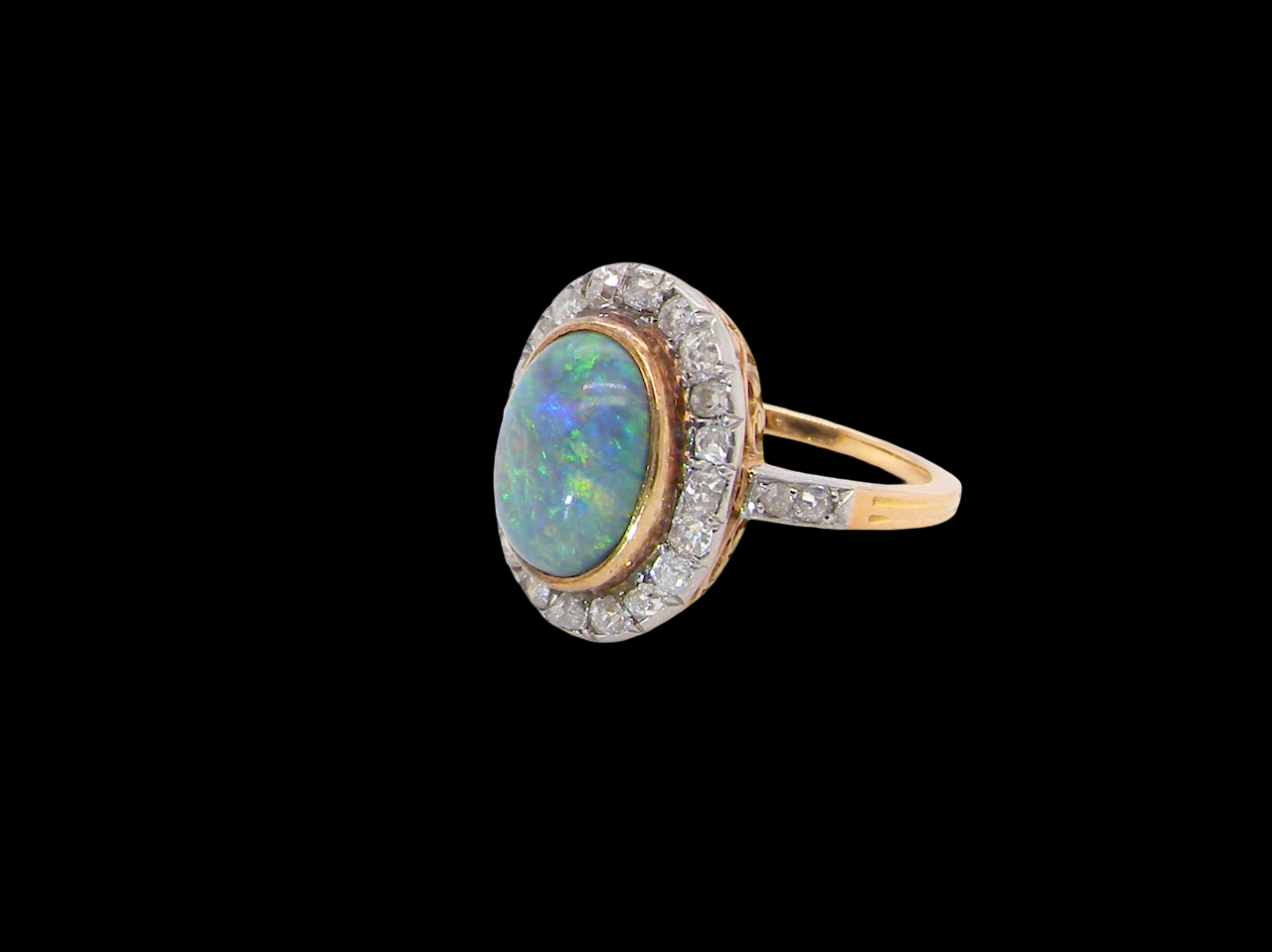 A vintage early 20th century cluster ring. Features to the centre a black opal doublet, with an excellent play of colour, measures 9.5x7.5mm, in a rim setting.
side