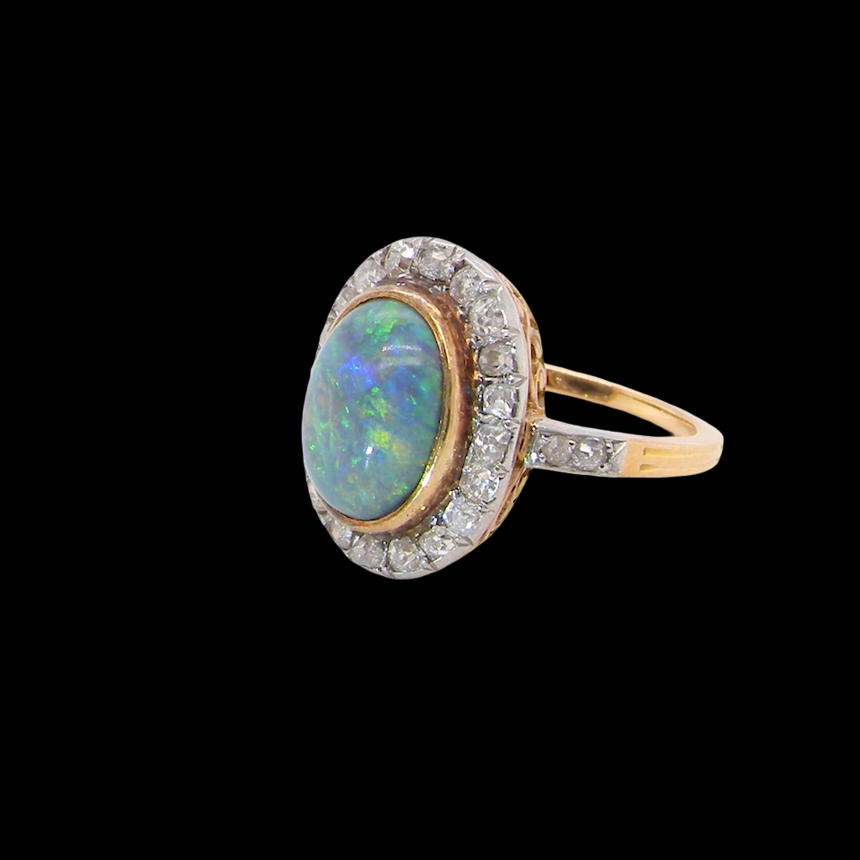 A vintage early 20th century cluster ring. Features to the centre a black opal doublet, with an excellent play of colour, measures 9.5x7.5mm, in a rim setting.
side