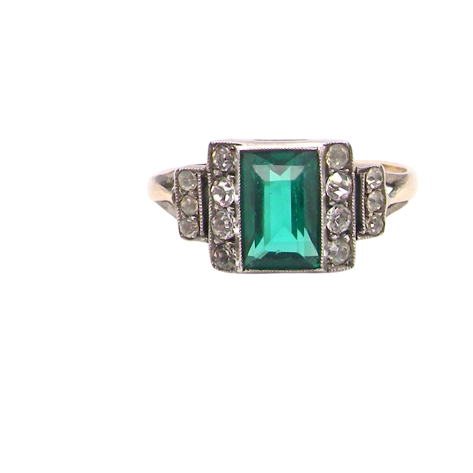 A vintage early 20th century dress ring. The centre stone a vibrant crystal clear green paste stone, 8x6mm.