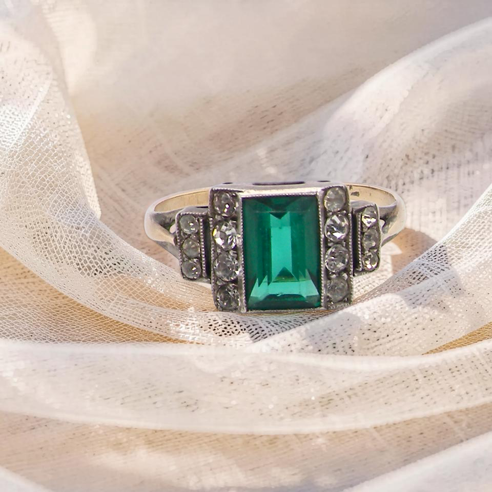 A vintage early 20th century dress ring. The centre stone a vibrant crystal clear green stone, 8x6mm.