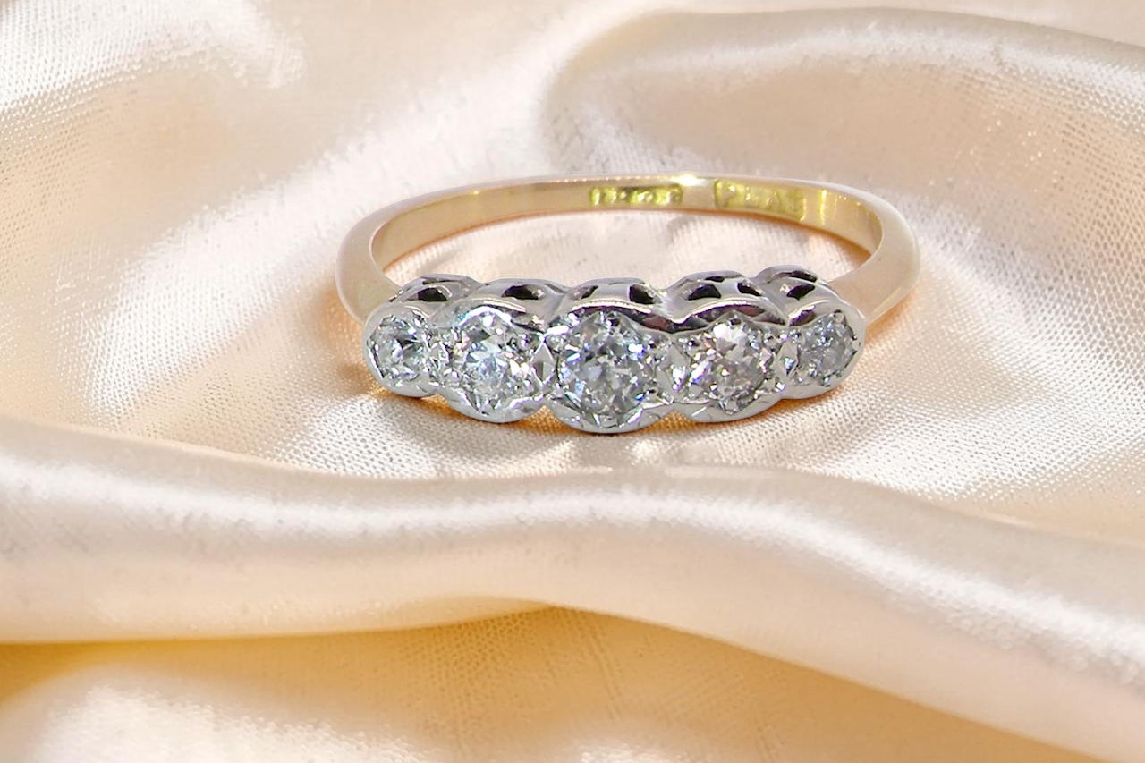 A vintage ring containing five old brilliant cut white diamonds. Centre 3mm, each side 2.2mm, at each end a 1.8mm diamond. Total diamond content estimated at 0.25 carats.