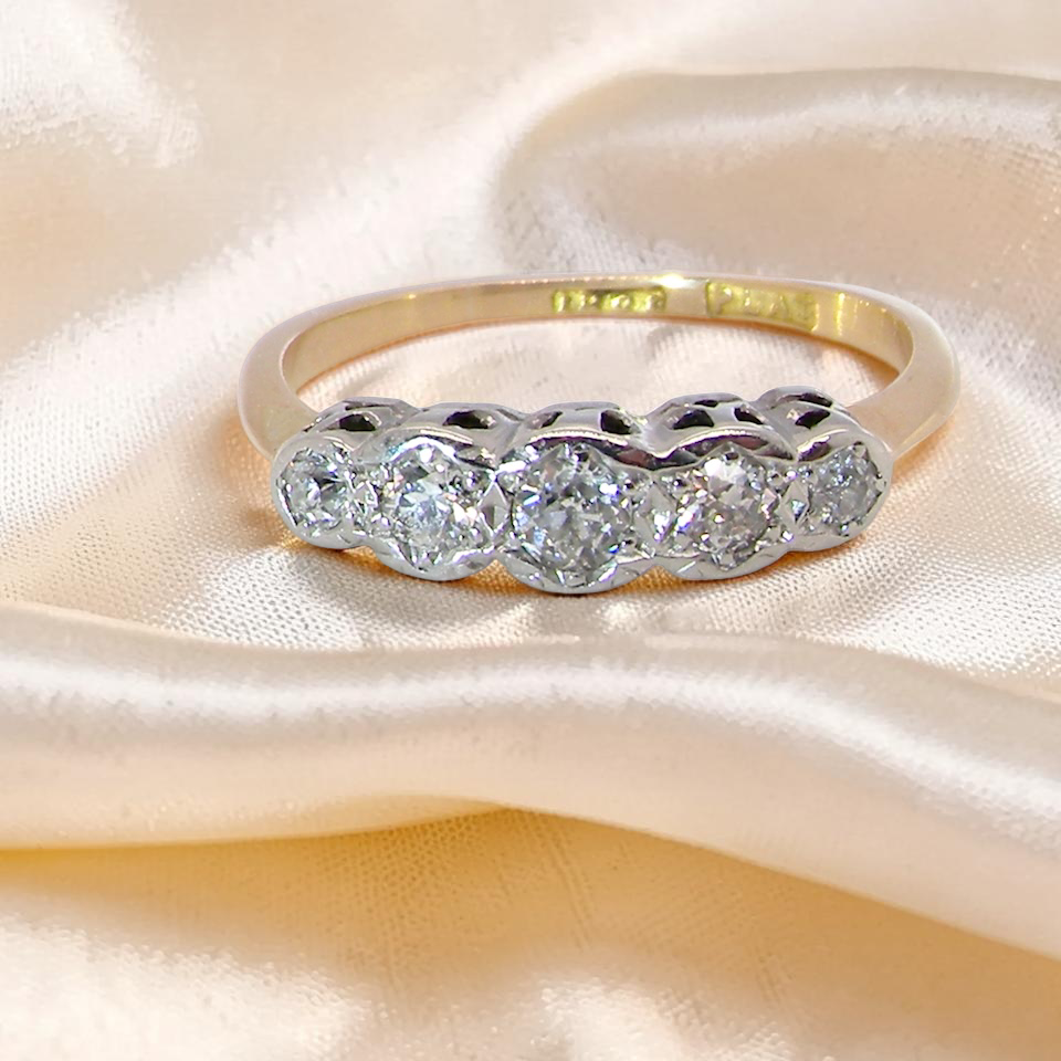 A vintage ring containing five old brilliant cut white diamonds. Centre 3mm, each side 2.2mm, at each end a 1.8mm diamond. Total diamond content estimated at 0.25 carats.